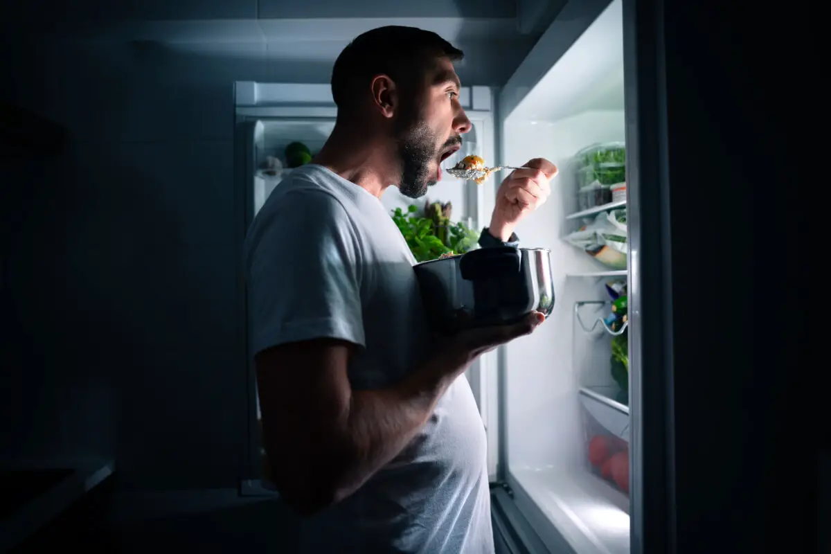 A man eating in front of fridge
